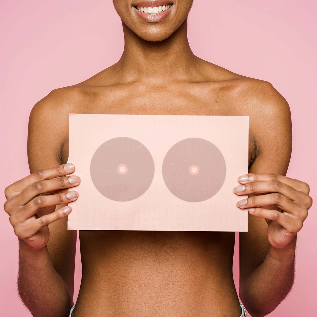 Woman holding a sign with an illustration depicting a breast to illustrate the article “Lipofilling or implants: which method for your breast augmentation?”