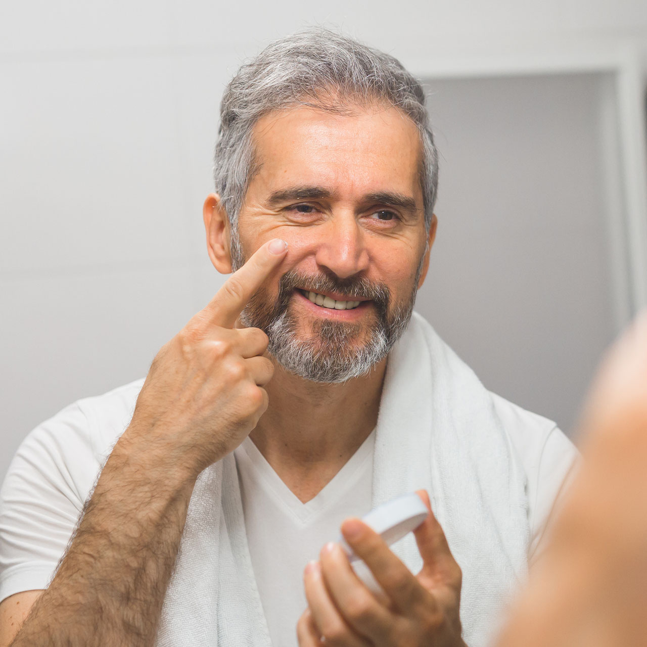 Image d'un homme d'âge mur se touchant le visage pour illustrer l'article sur les 3 chirurgies esthétiques les plus demandées par les hommes.